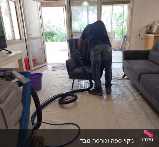 אדם מנקה ספה עם מכונת ניקוי ושואב אבק